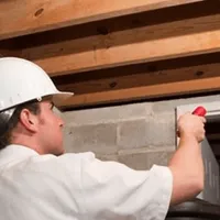 Termite inspection technician checking a basement wall and framing for termite activity in Reno, NV